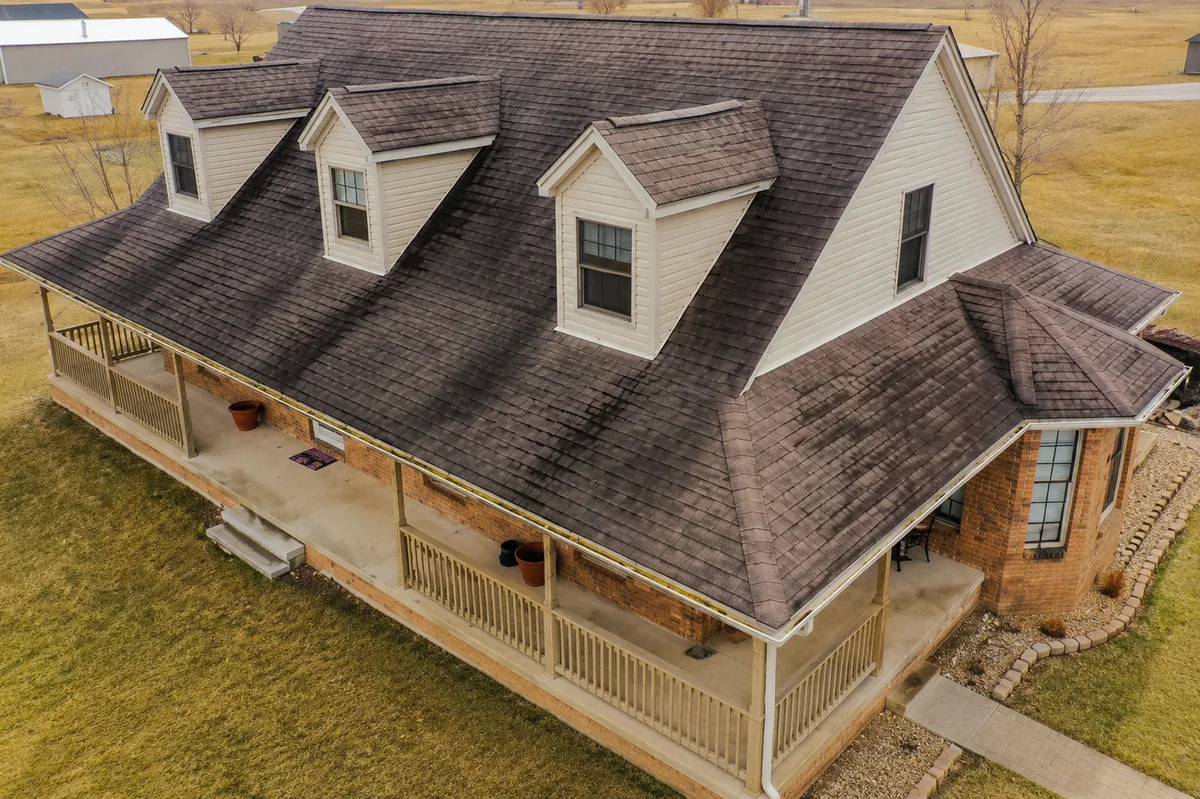 Aerial view of a home with a weathered, discolored asphalt roof nearing the end of its life