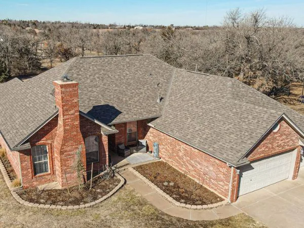 A brick home with a newly installed shingle roof, seen from above